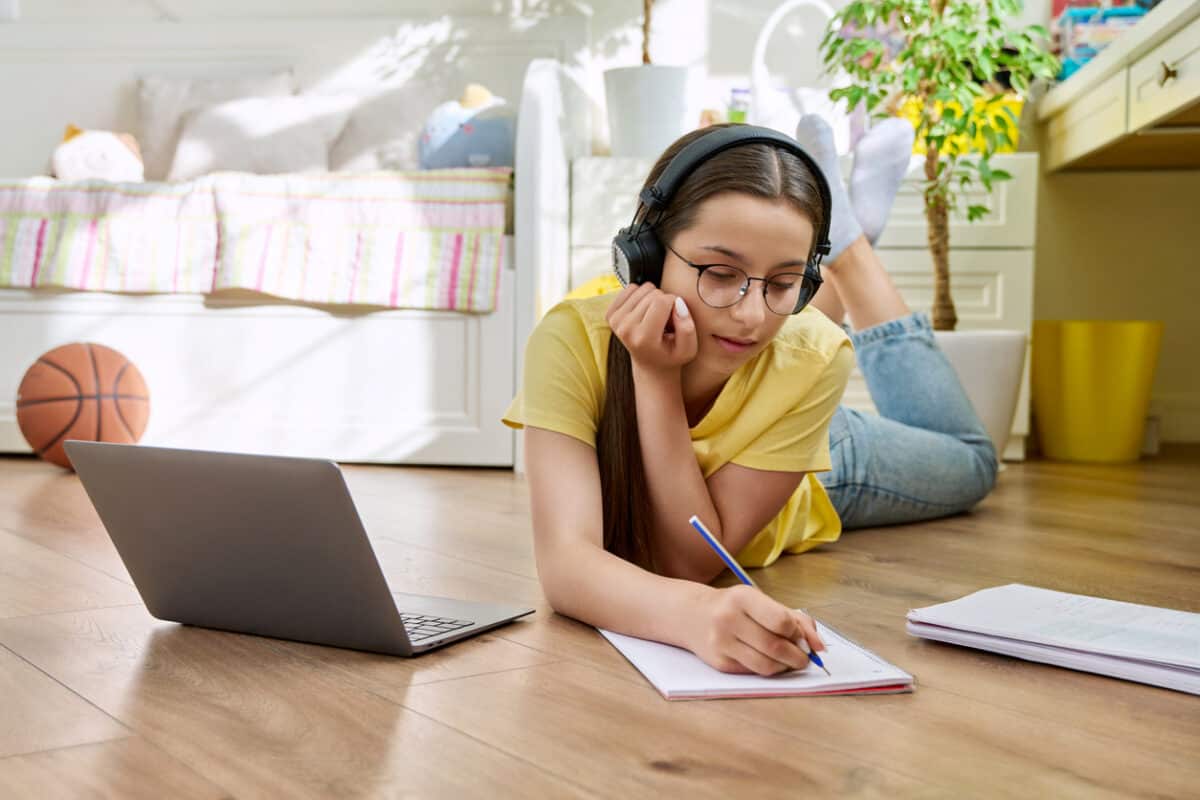 Teenage with glasses studying at home using a laptop