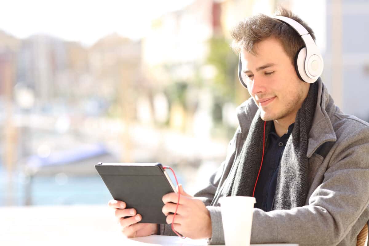 Man using tablet with headphones in outdoor space.