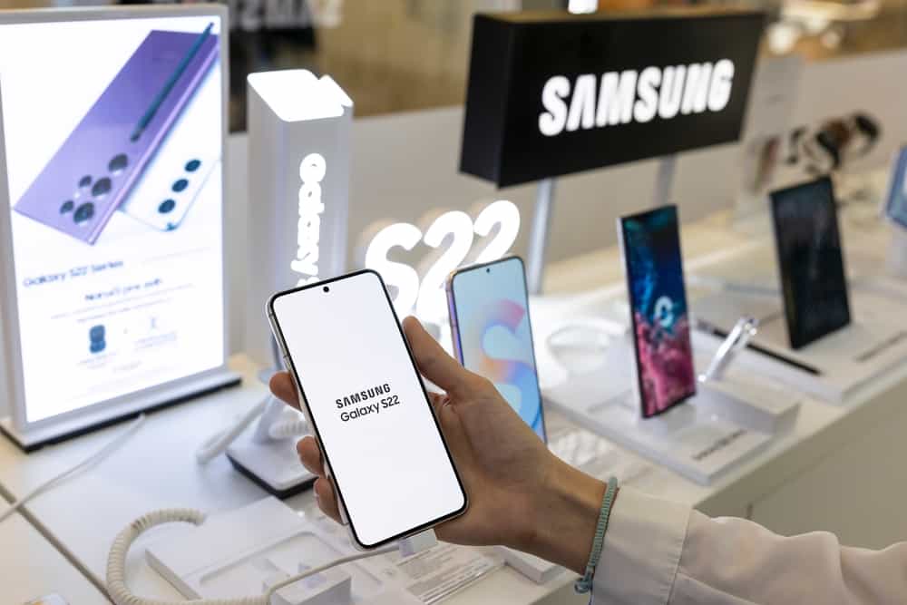 A customer holding a Samsung Galaxy s22 on display at a smartphone store