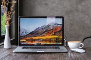 Macbook Pro on a desk with a vase and tea cup