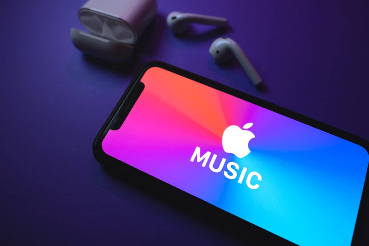 Apple Music logo on an iPhone screen near a pair of AirPods and charging case.