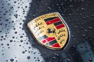 Porsche logo on a black car with raindrops