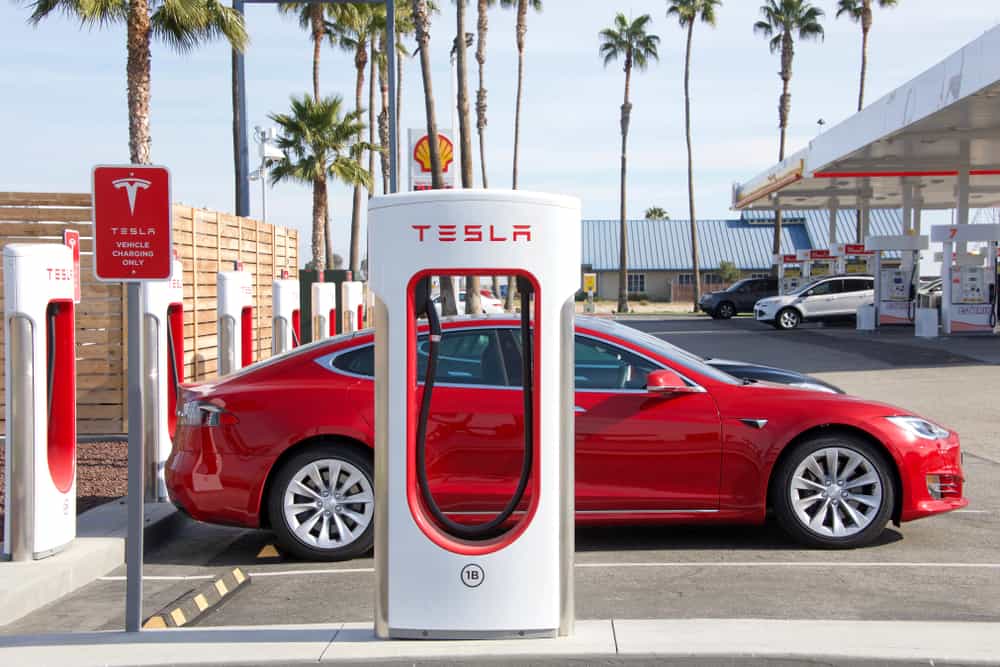 a red tesla plugged into a fast charger