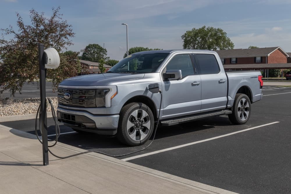 grey Ford F-150 EV pickup truck plugged to a power charger