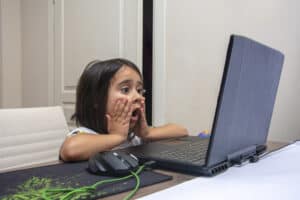 Little girl shocked looking at computer laptop