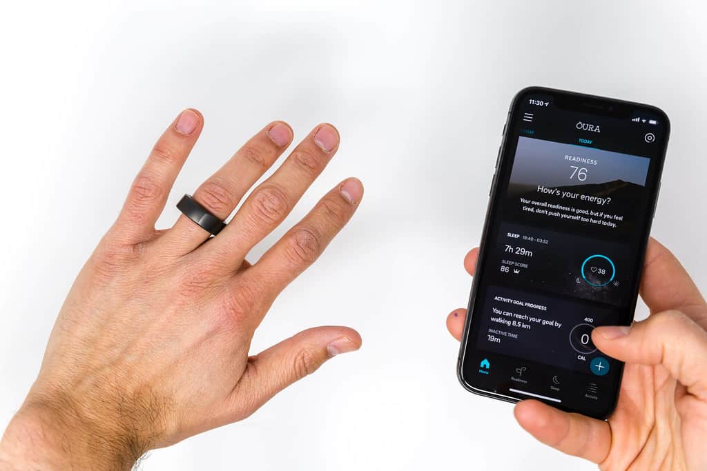 Oura Ring on a finger next to a smartphone