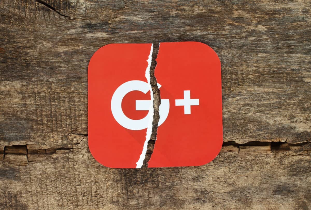 Torn Google plus icon paper on old wooden background