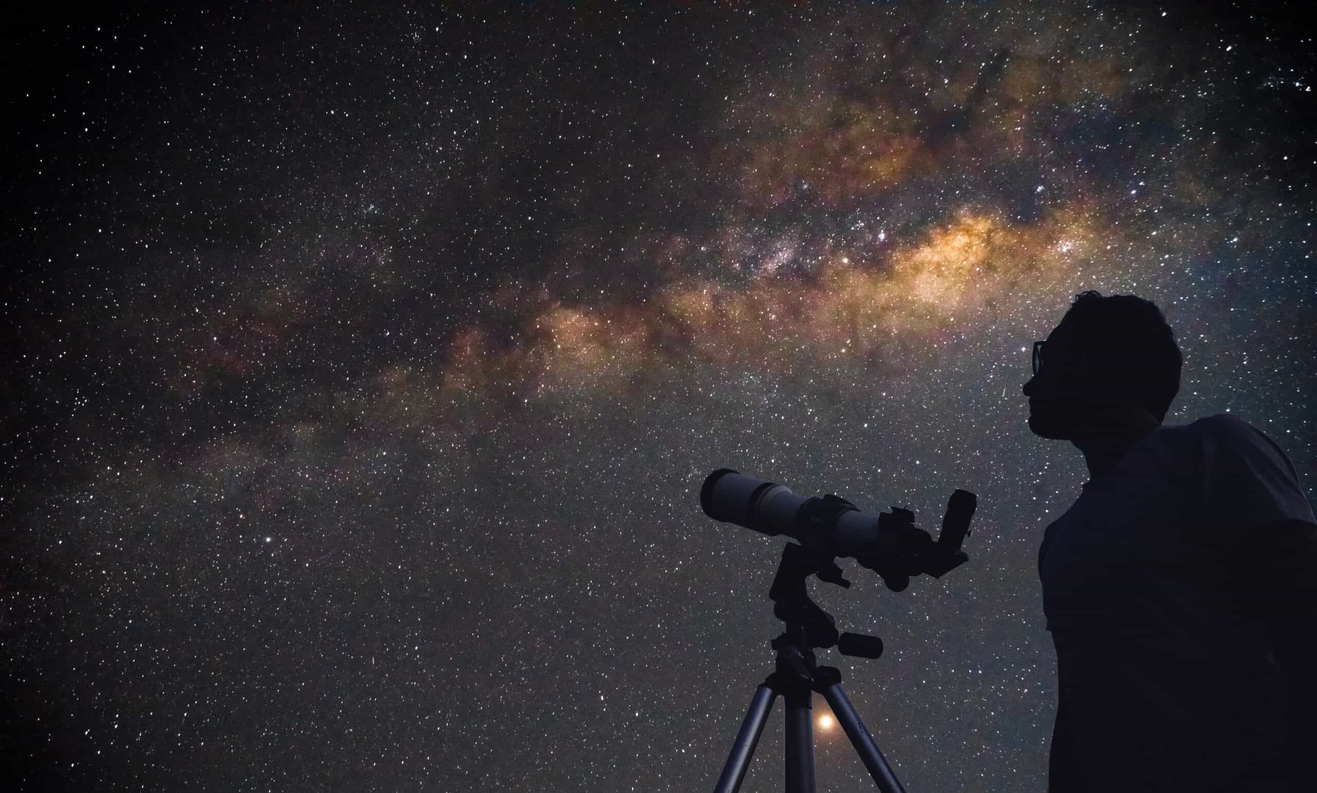 Astronomer with a telescope watching at the stars and Moon.