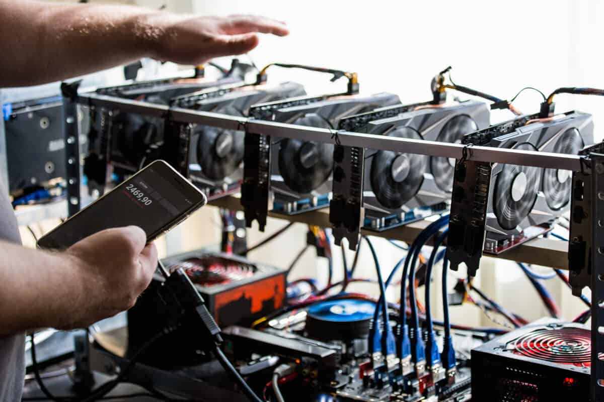 man with a phone checking temperature of a mining rig.