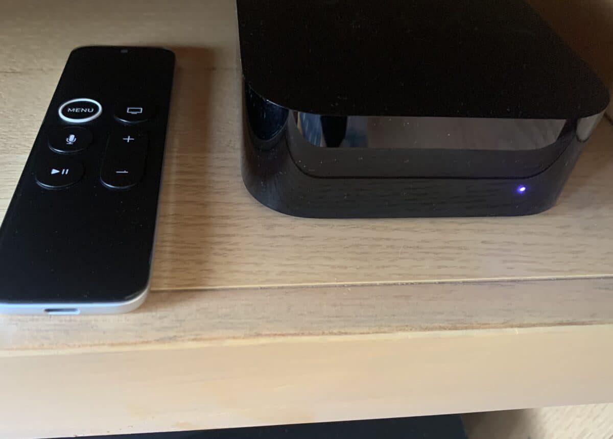 Apple TV Siri Remote placed next to Apple TV 4K device.