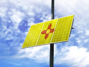 Solar panels against a blue sky with a picture of the flag State of New Mexico