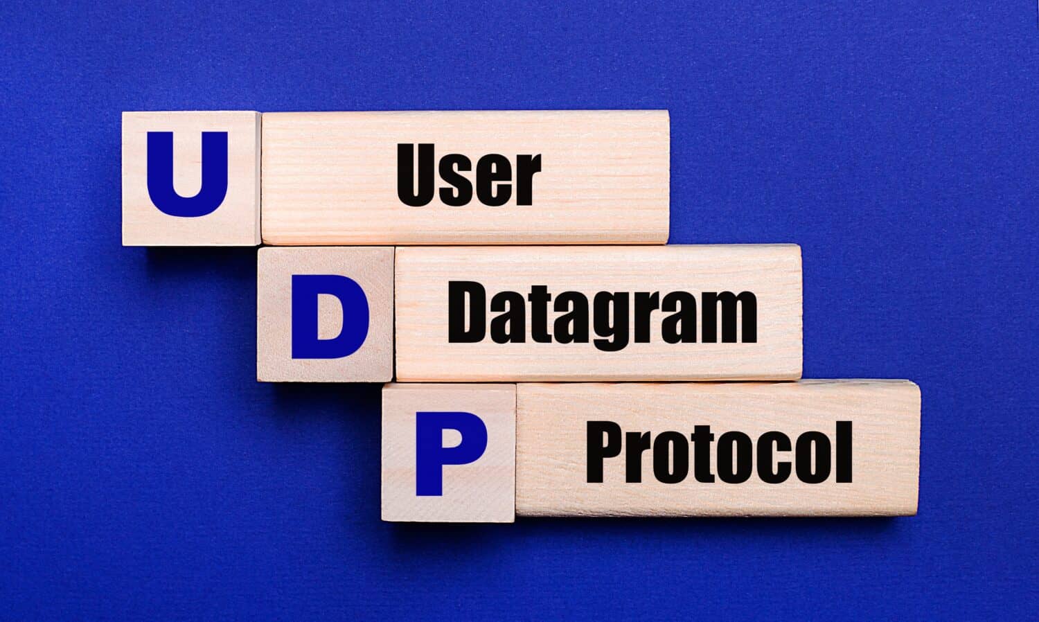 On a bright blue background, light wooden blocks and cubes with the text UDP User Datagram Protocol