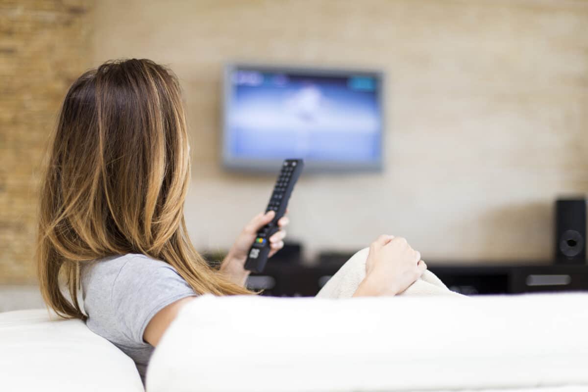 woman watching tv holding remote