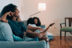 women on couch watching tv with remote