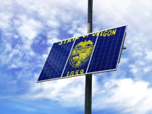 Solar panels against a blue sky with a picture of the flag State of Oregon