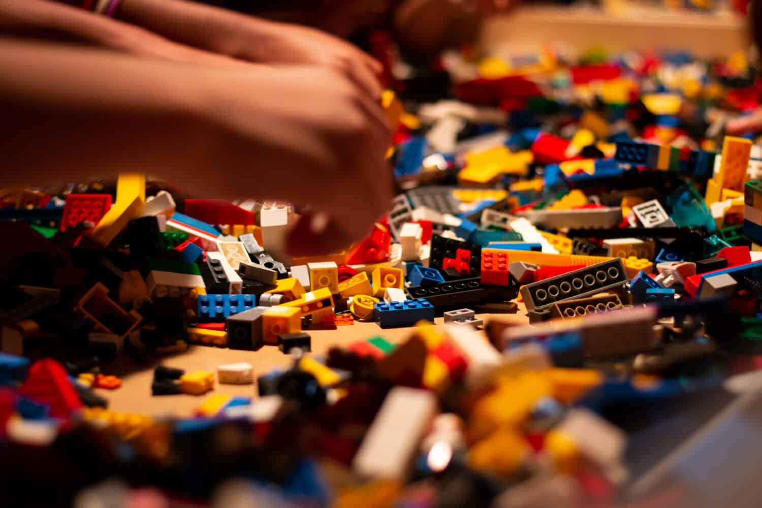 Huge pile of colorful lego bricks with childrens hands