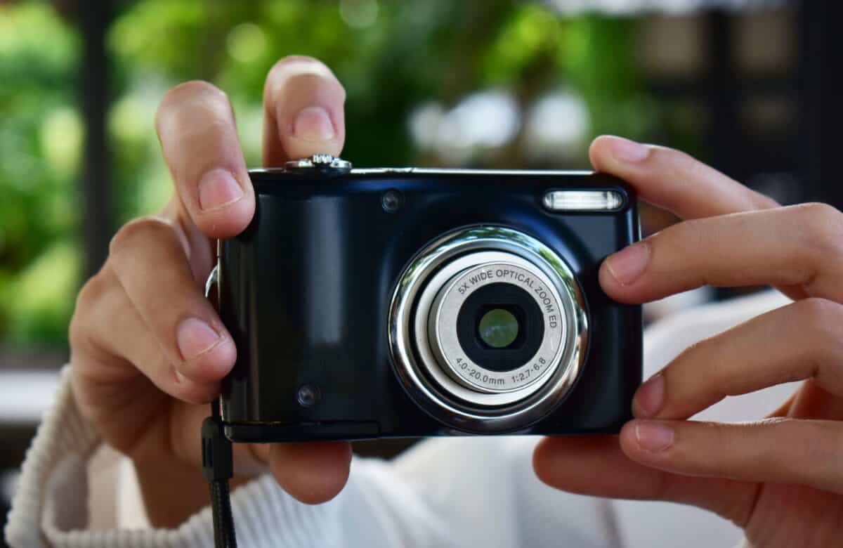 Compact digital camera Black in hand with open lens
