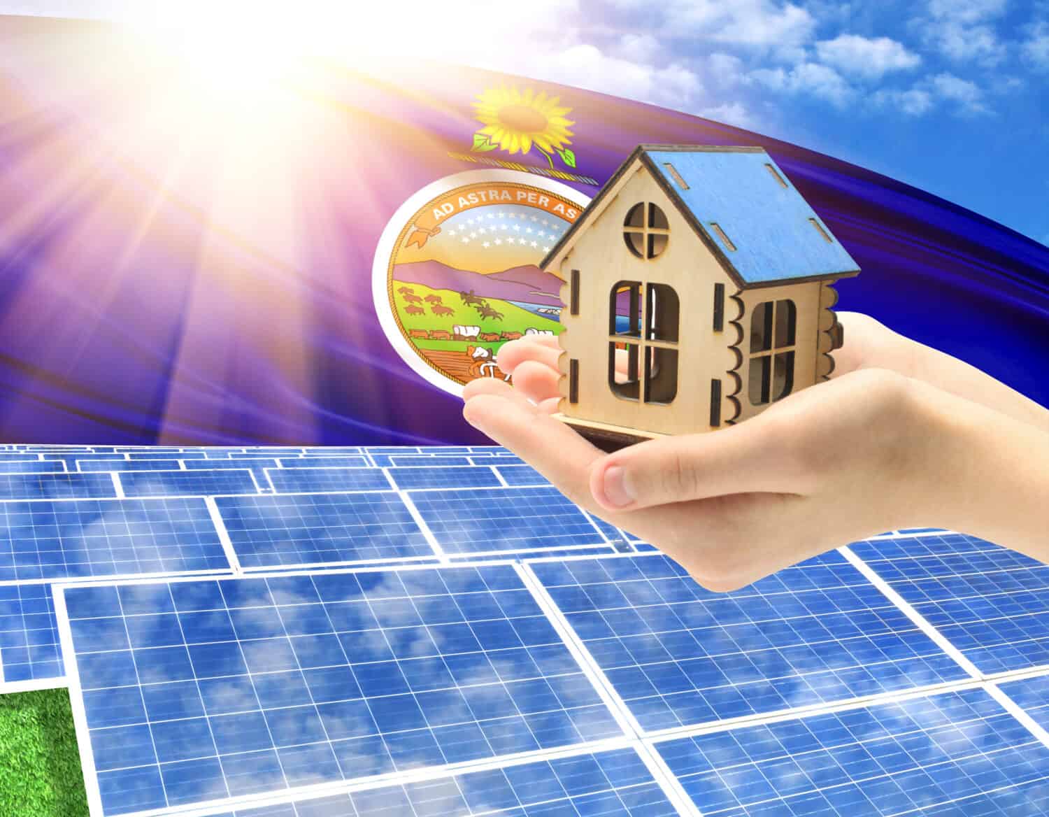 The photo with solar panels and a woman's palm holding a toy house shows the flag State of Kansas in the sun.