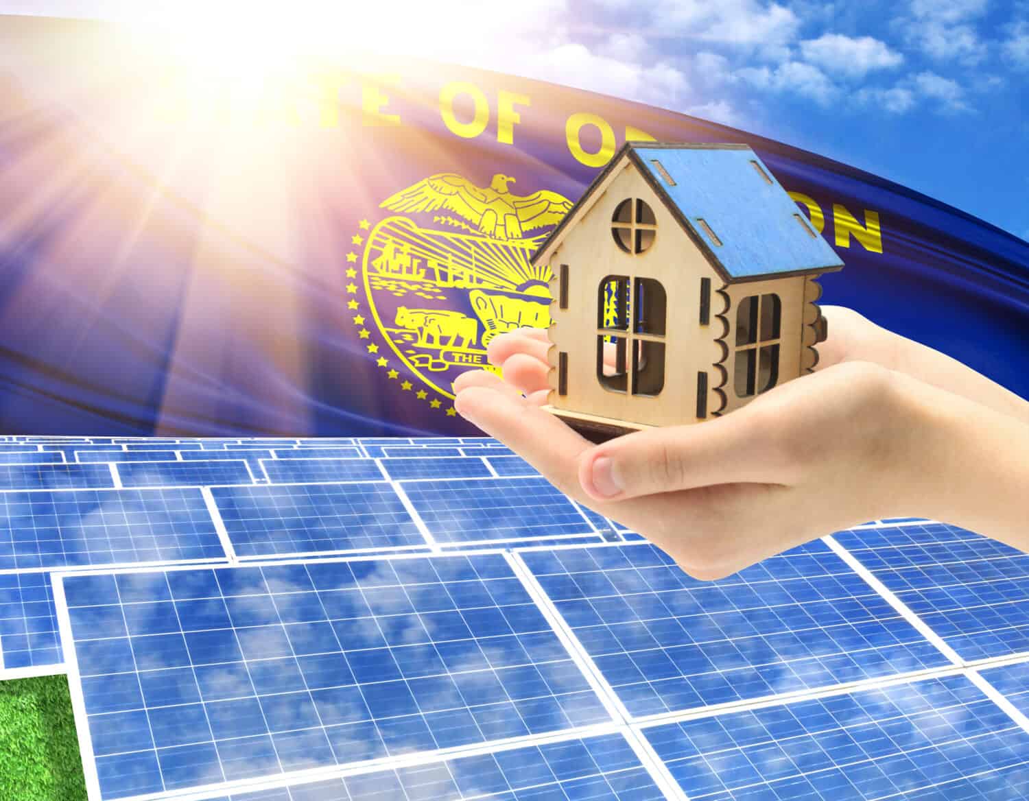 The photo with solar panels and a woman's palm holding a toy house shows the flag State of Oregon in the sun.