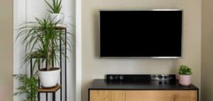 smart tv mockup hanging on beige wall in modern interior with green plants