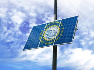 Solar panels against a blue sky with a picture of the flag State of South Dakota