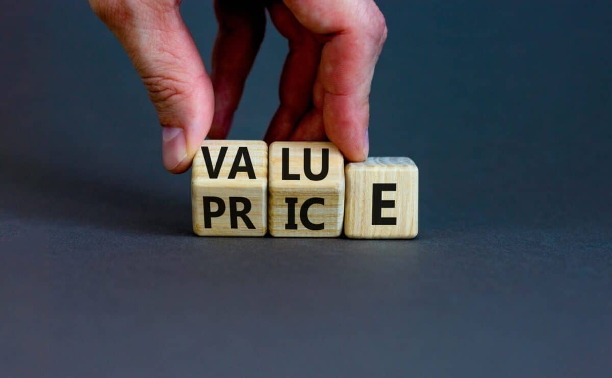 Value and price symbol. Businessman turns wooden cubes and changes the word price to value or vice versa. Beautiful grey table, grey background, copy space. Business value and price concept.