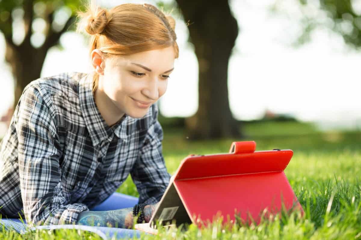 Woman in a park using one of the best iPad cases to prop up her tablet