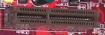 A closeup of a communications and networking riser slot on a red motherboard.