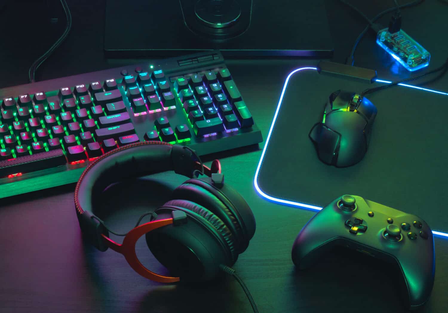 Khái niệm không gian làm việc của game thủ, xem hàng đầu một thiết bị chơi game, chuột, bàn phím, cần điều khiển, tai nghe, cần điều khiển di động, trong tai nghe tai và miếng đệm chuột với màu RGB trên nền bàn màu đen
