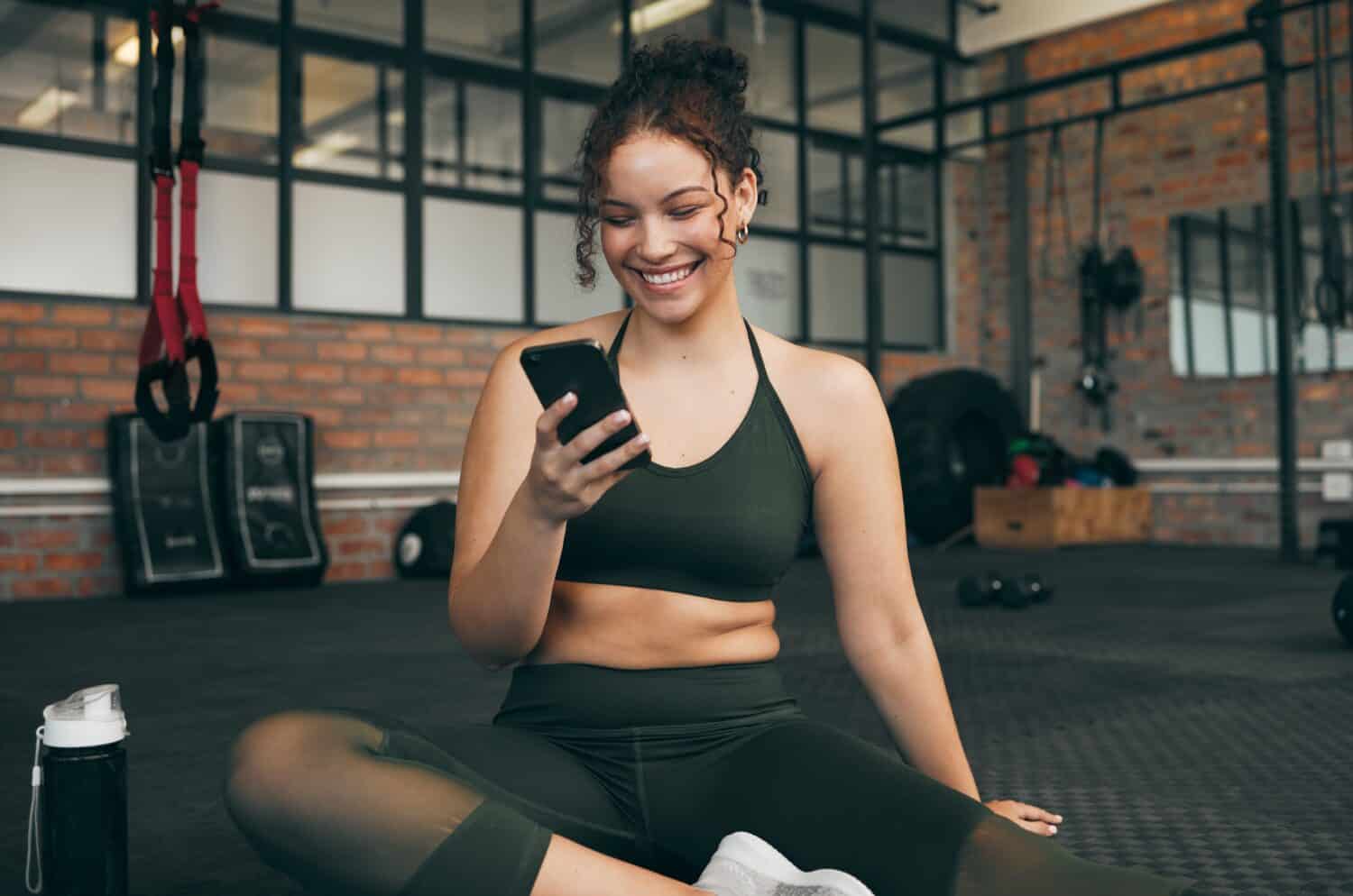 Happy woman in a gym using the best workout app