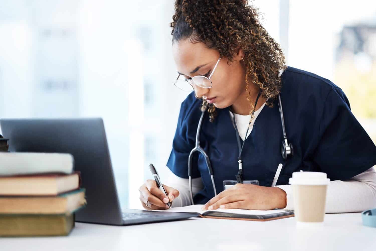 Medical student, thinking or writing books in research education, wellness studying or hospital learning. Laptop, nurse or healthcare woman and notebook, technology or scholarship medicine internship