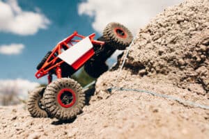 Suv overcoming rock rise, close-up. Rc crawler riding through mountain landscape. Truck overpass offroad rally trace.