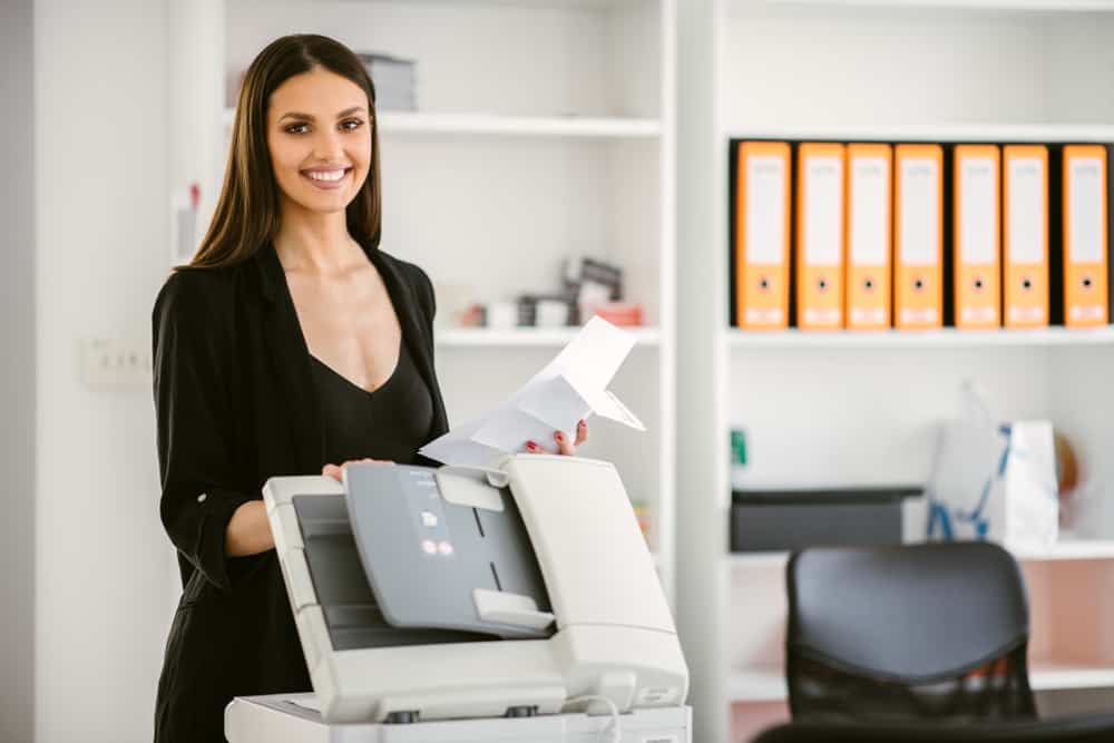 Business woman using a printer. Beautiful business woman printing a document. Business woman printing a document for a new company project.