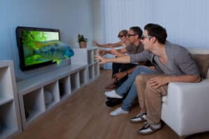 Conceptual image of a family watching 3D television and stretching out their hands as though to touch the image on the screen