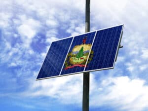Solar panels against a blue sky with a picture of the flag State of Vermont