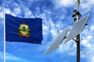 Solar panels on a background of blue sky with a flagpole and the flag State of Vermont