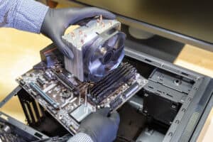Upgrade or PC assembly concept. Technician installs a new motherboard with a large CPU cooler in a computer case
