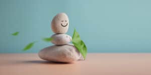 Enjoying Life, Harmony and Positive Mind Concept. Stack of Stable Pebble Stone with Smiling Face Cartoon and Leaf. Serene, Balancing Body, Mind, Soul and Spirit. Mental Health Practice