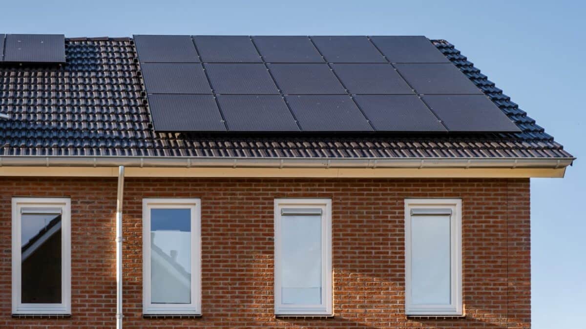 Newly build houses with solar panels attached on the roof against a sunny sky Close up of a new building with black solar panels. Zonnepanelen, Zonne energie, Translation: Solar panel, , Sun Energy.