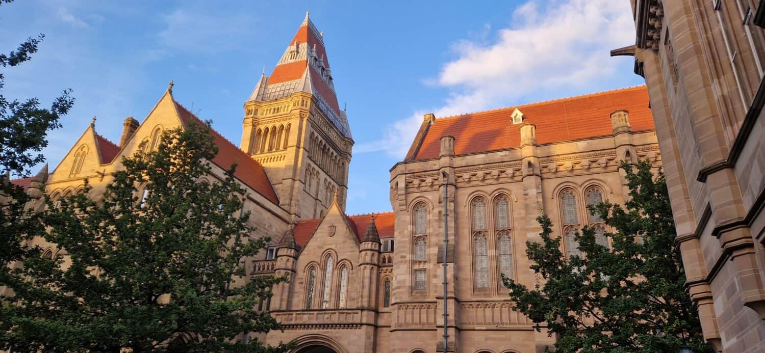 Manchester University Campus Large Old Building Red Brick Roof with Trees and Blue Sky