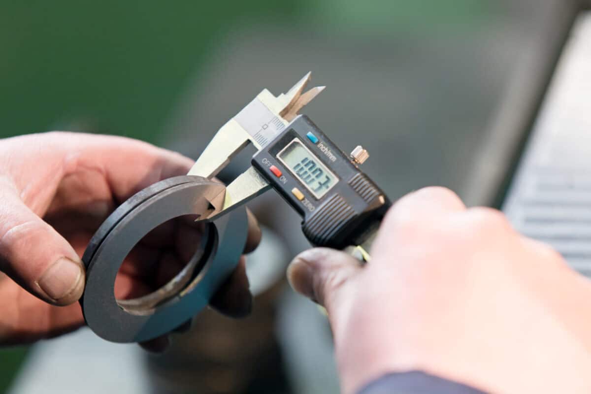Factory man worker measuring steel detail with digital Vernier Caliper at workshop