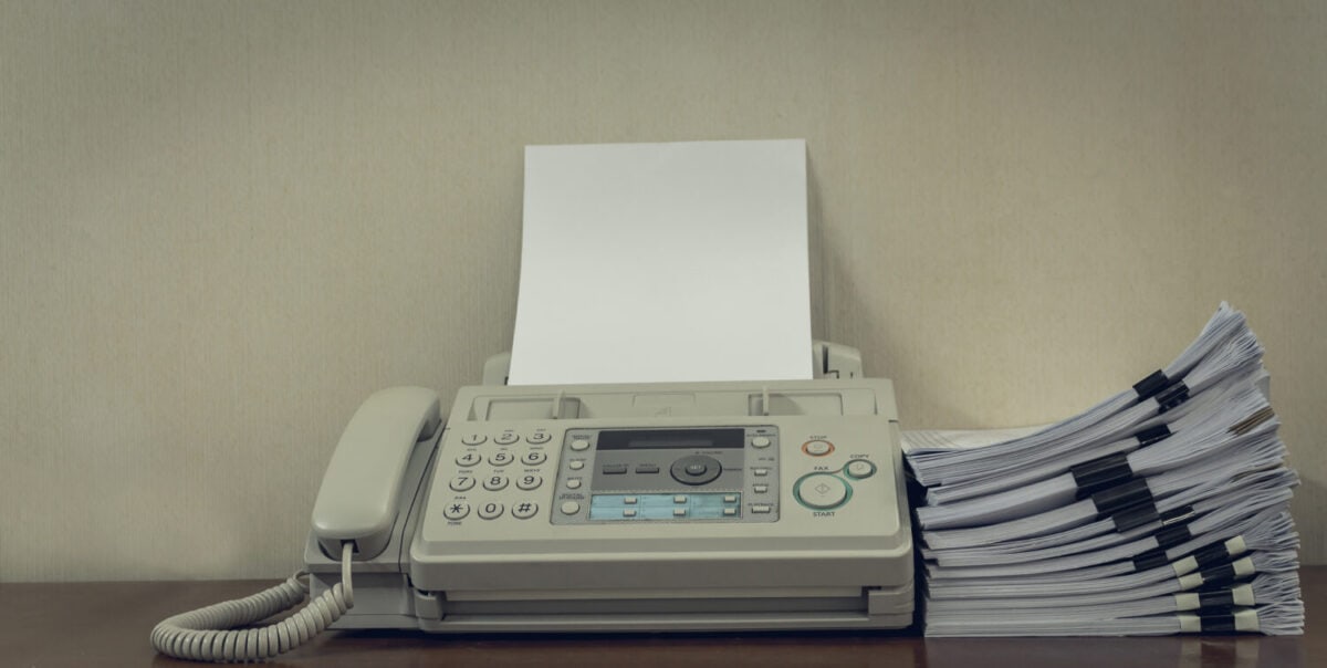 old fax machine on the table and stack of paper.