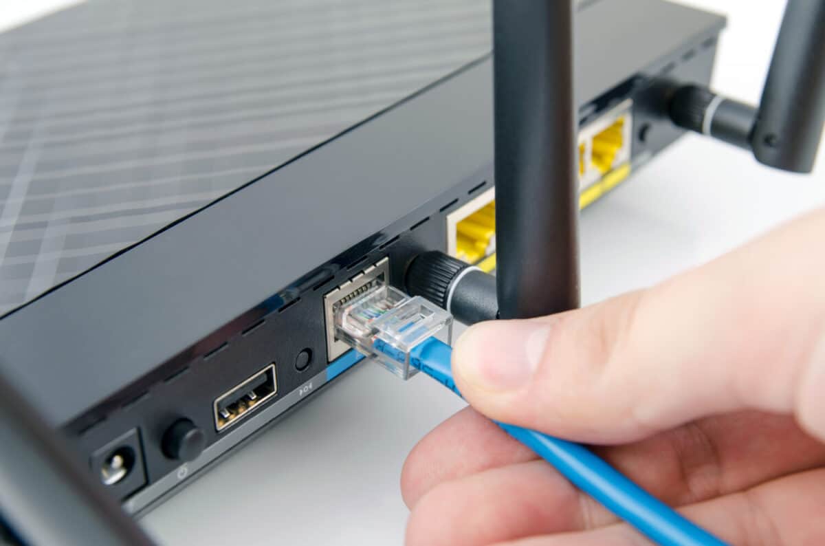 Man plugs internet cable into the router. router wifi ethernet connection network port wireless closeup concept