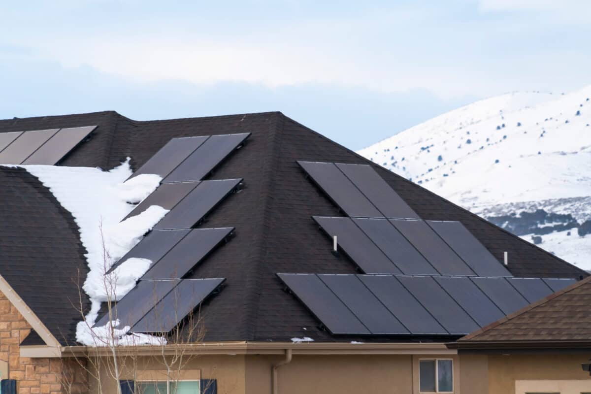 Solar panels installed on the dark roof of a home with snow in winter