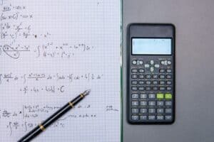 scientific calculator next to a notebook with math calculations. Counting integrals