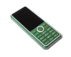 Green push-button mobile phone on a white background. The mobile phone is at a 45 degree angle.
