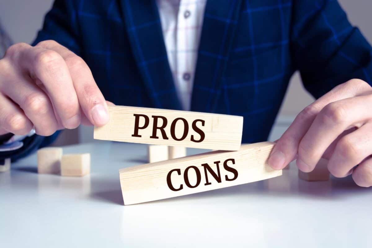 Close up on businessman holding a wooden block with "Pros or Cons?" message