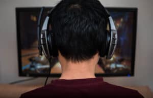 Featured image for Overwatch parents guide. Gamer in headphone playing video game at home.