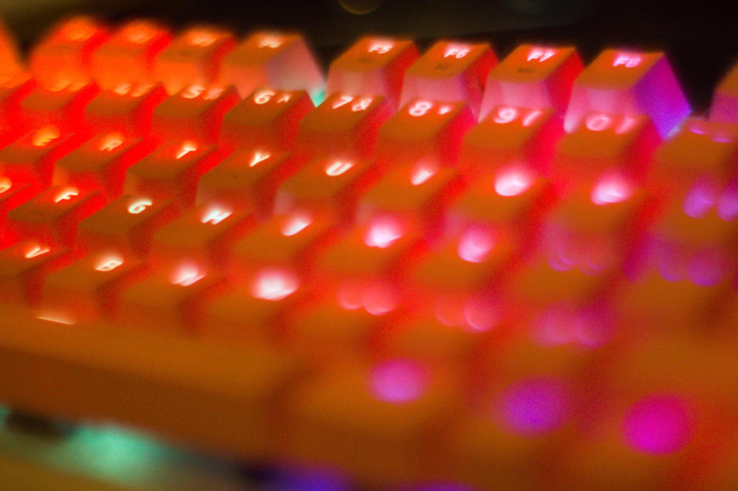 A close up of a Razer BlackWidow X Chroma Mercrury keyboard with pink keycaps and a blurred foreground.