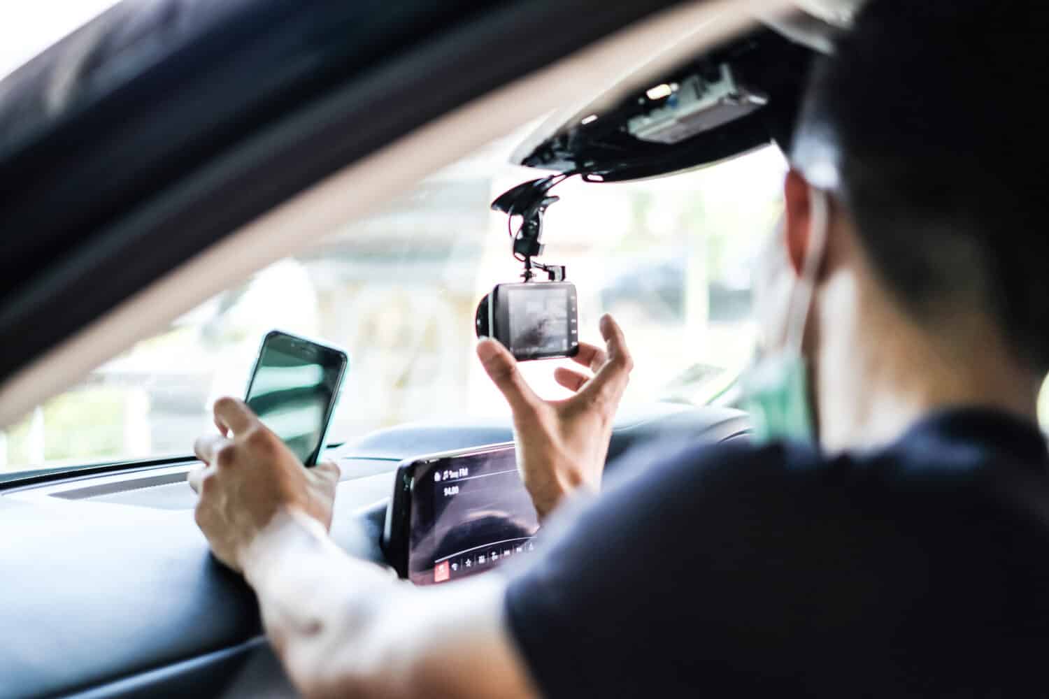 Close up Technician Hand with Car Camera and Smartphone Inside Car and Blur Man as a Foreground
